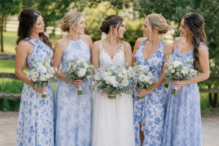 Bridesmaids in blue floral bridesmaid dresses in flowing chiffon maxi gowns at a romantic outdoor garden wedding