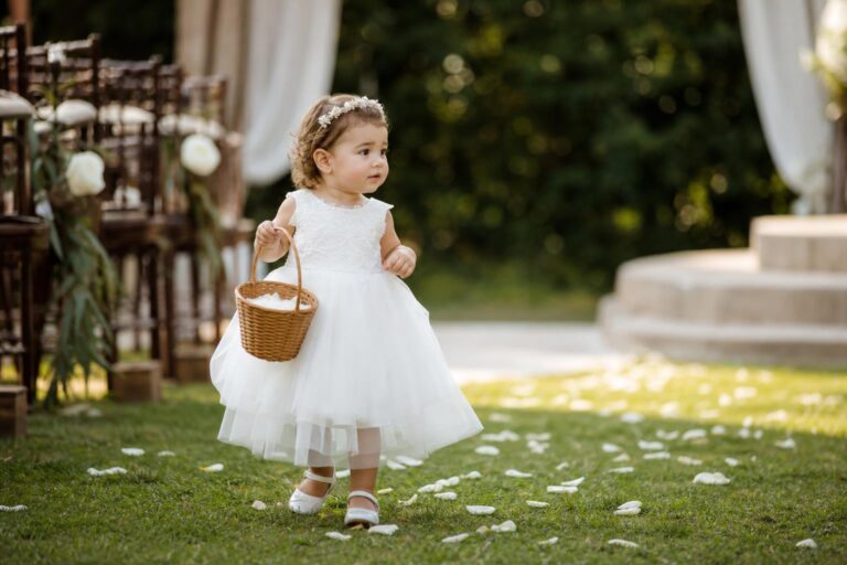Flower girl dresses toddler in ivory lace and tulle, a toddler walking down a wedding aisle in soft natural light