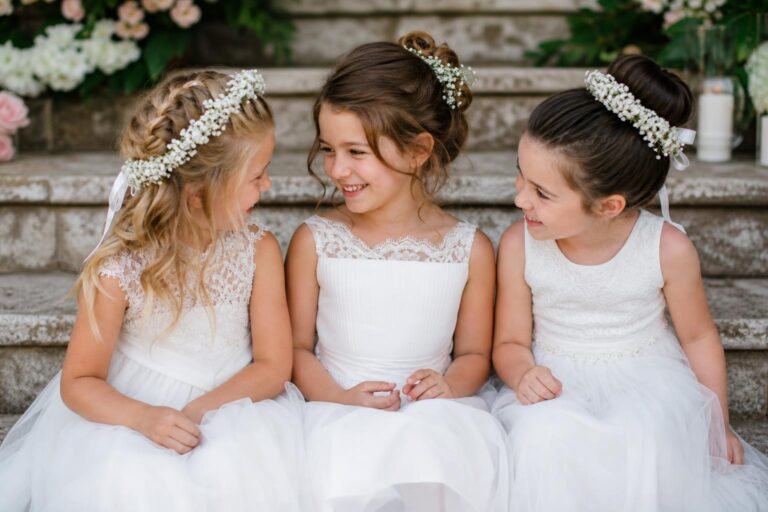 Kids hairstyles for wedding with a crown braid and ribbon on a flower girl in a spring garden ceremony