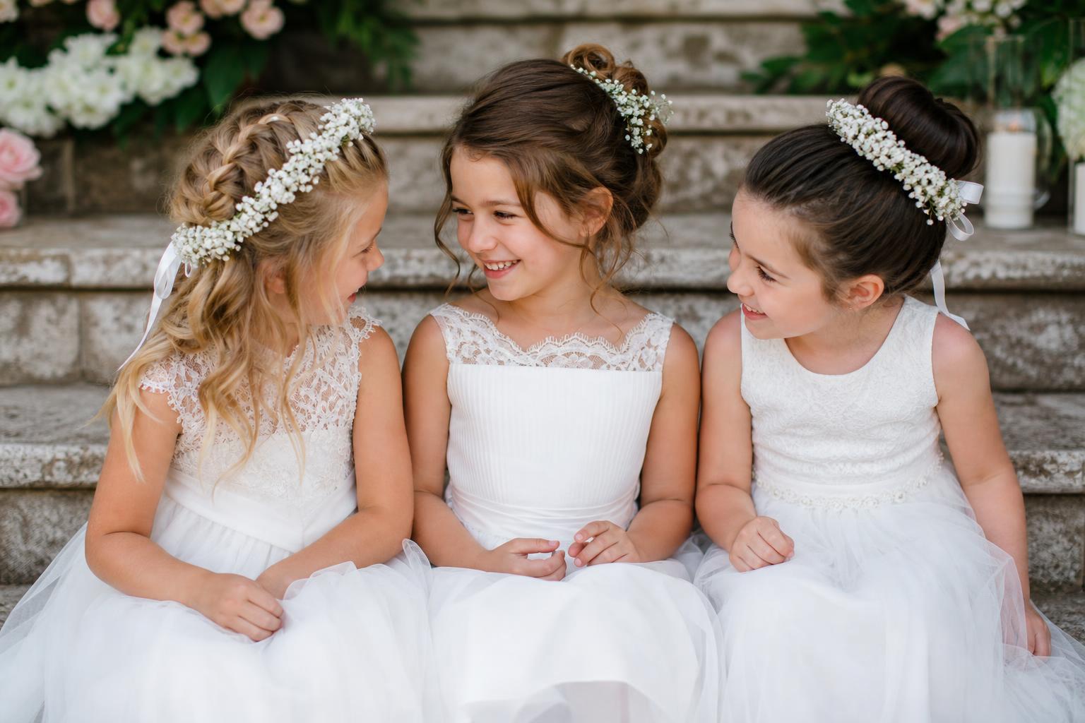 Kids hairstyles for wedding with a crown braid and ribbon on a flower girl in a spring garden ceremony