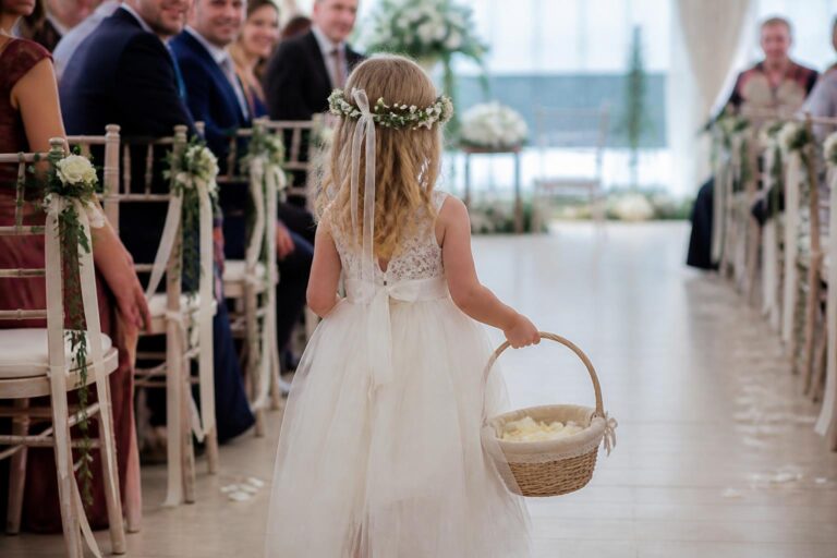 Romantic flower girl basket with lace trim and rose petals, held by a child walking down a wedding aisle