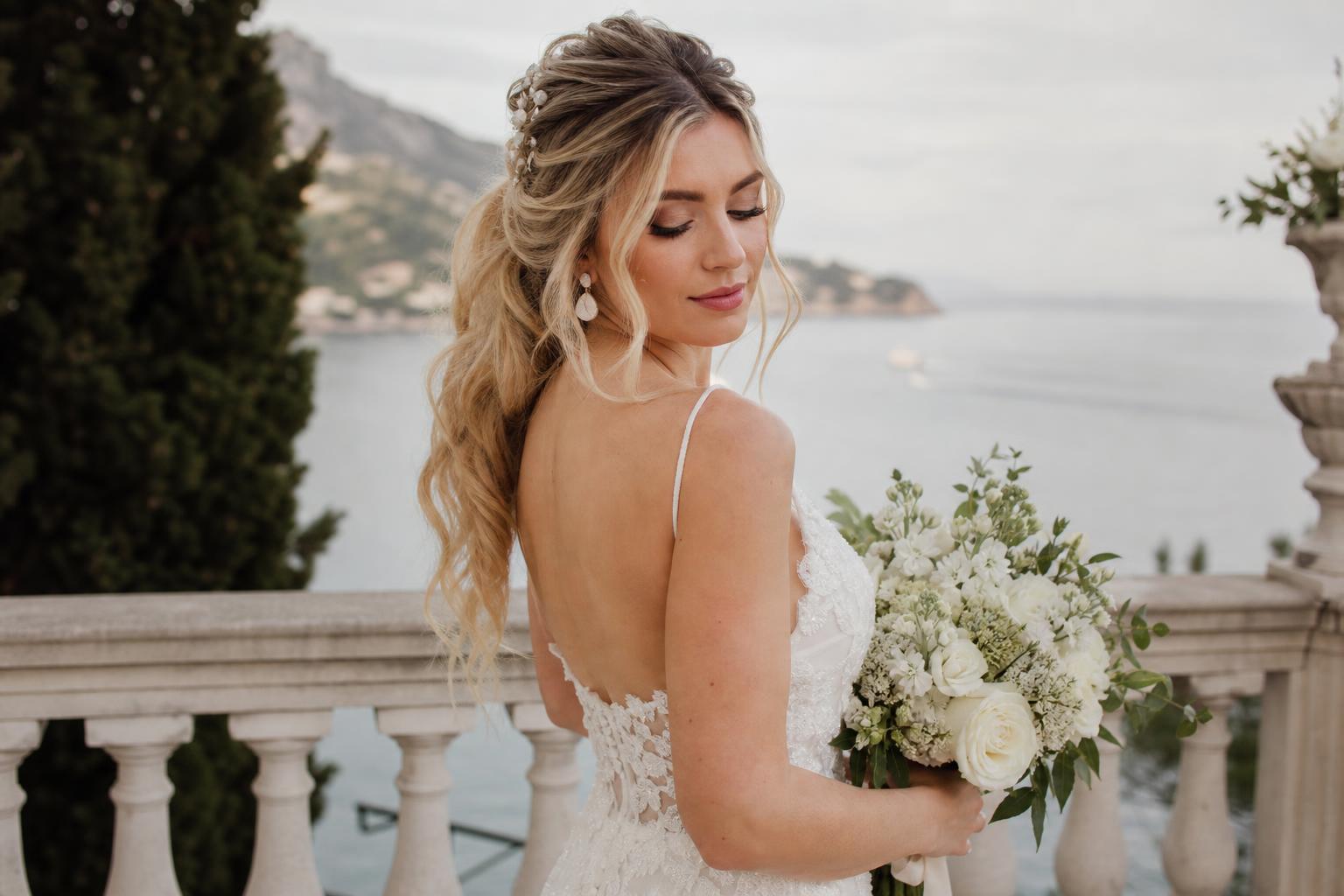 Wedding hairstyles for long hair in a romantic low bun with veil and pearl pins, photographed in soft spring light