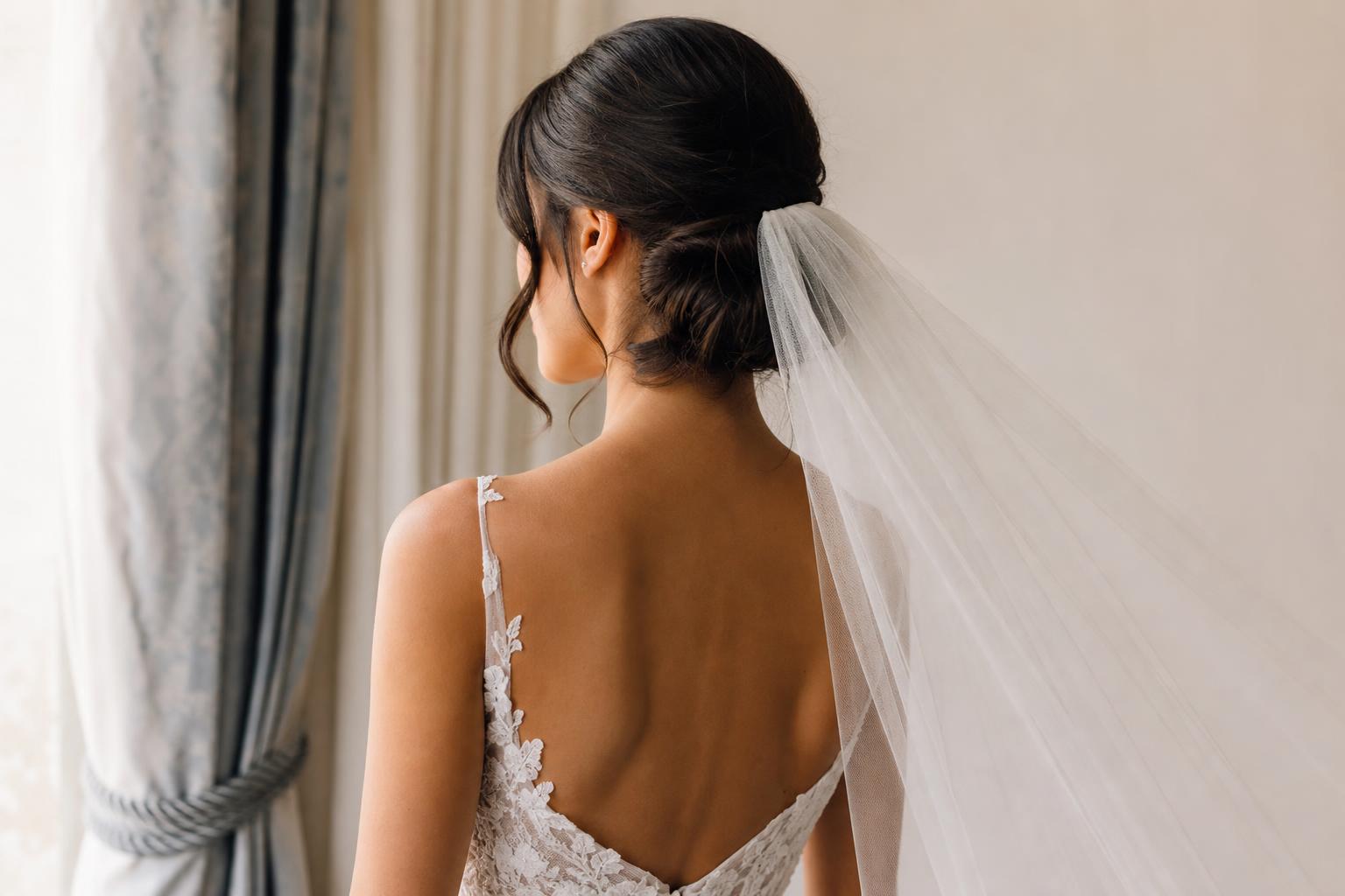 Wedding hairstyles with veil featuring a low chignon and fingertip tulle veil, softly structured for elegant bridal portraits