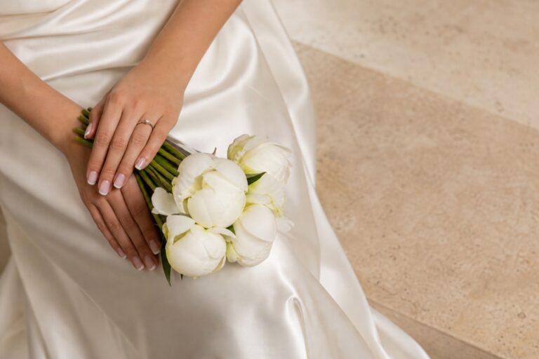 Pearl color nails with a gold ring, cream peonies, and ivory bridal details
