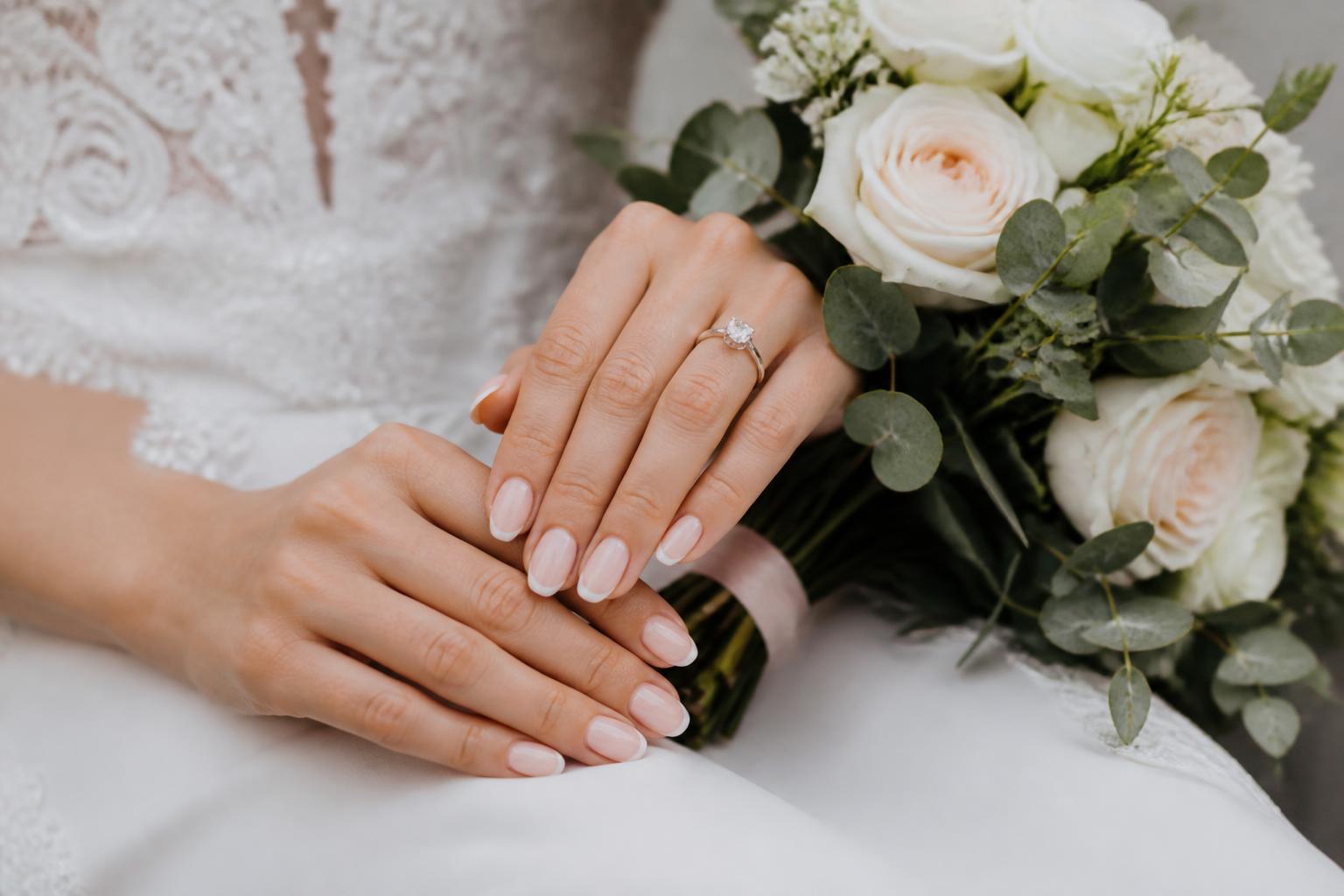 Simple wedding nails in glossy nude pink on almond-shaped fingers, photographed close-up for a timeless bridal manicure